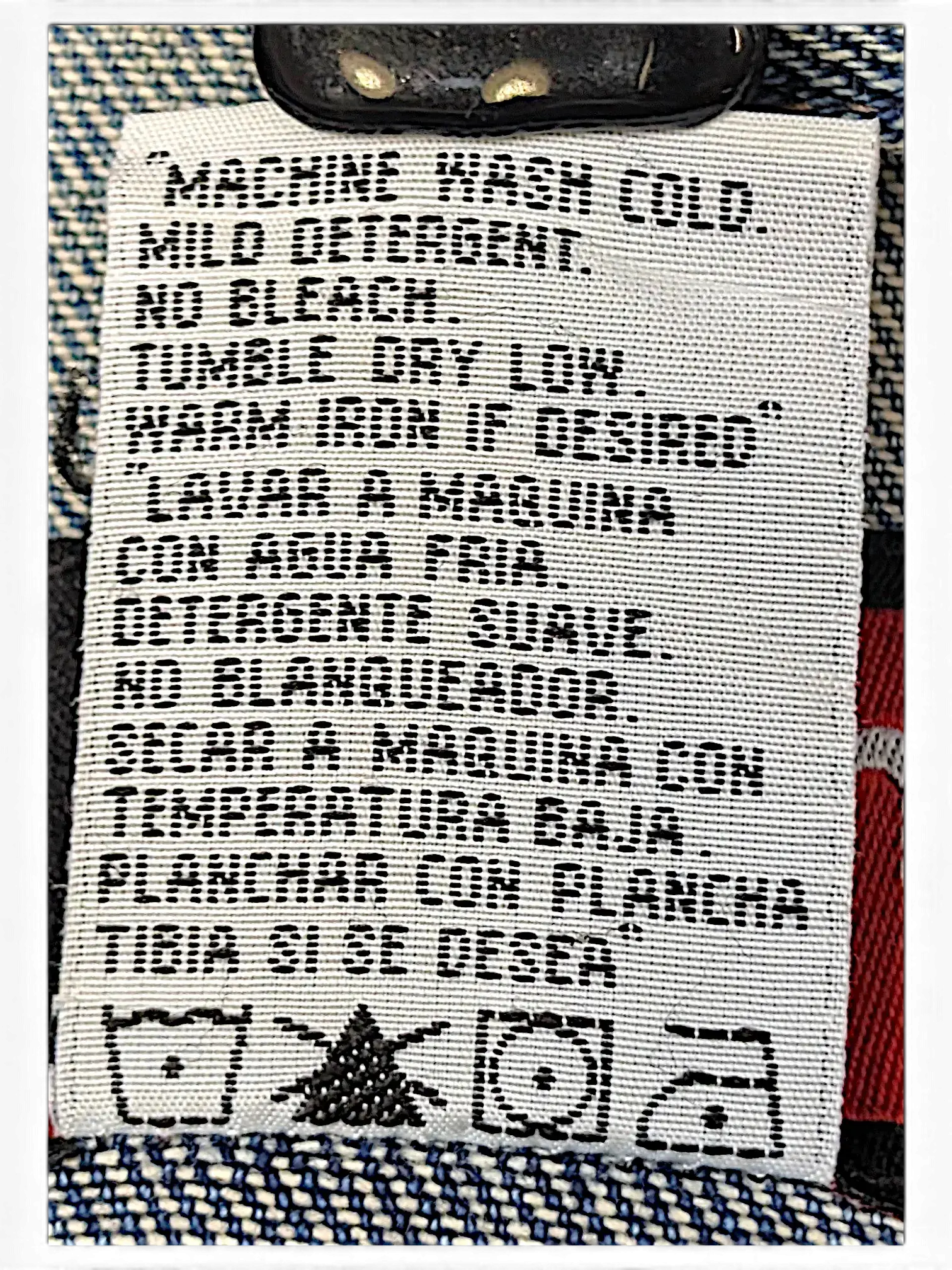 JAKE & IPI Wrangler Hero denim jacket care label with washing instructions in English and Spanish on blue denim