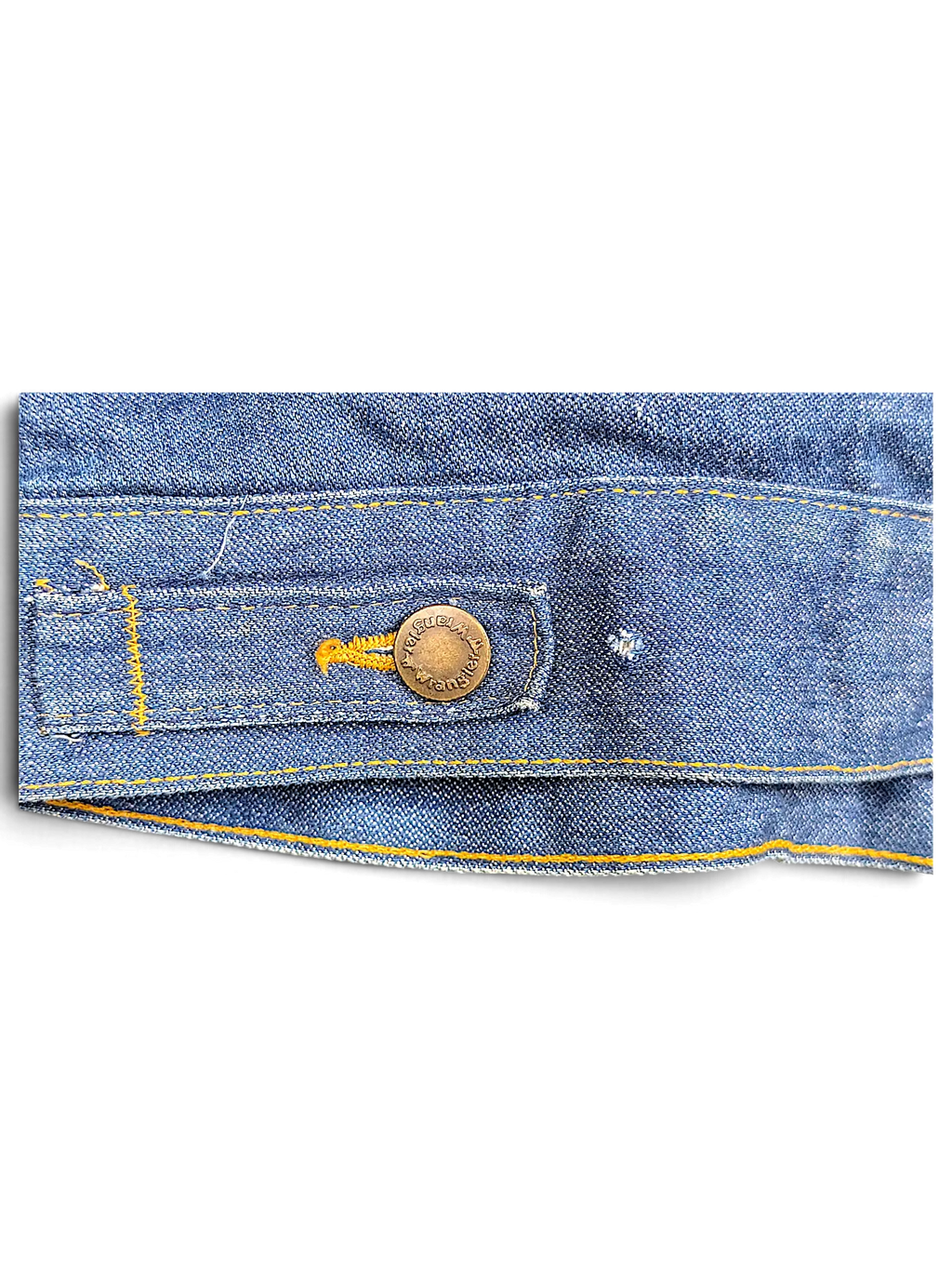 Close-up of a vintage blue denim Wrangler 80/90's Sherpa Jacket hem with a branded metal button by JAKE & IPI