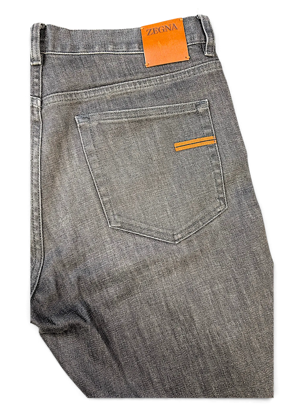 JAKE & IPI grey Zegna denim jeans featuring a leather brand patch and orange accent stitching on the back pocket.