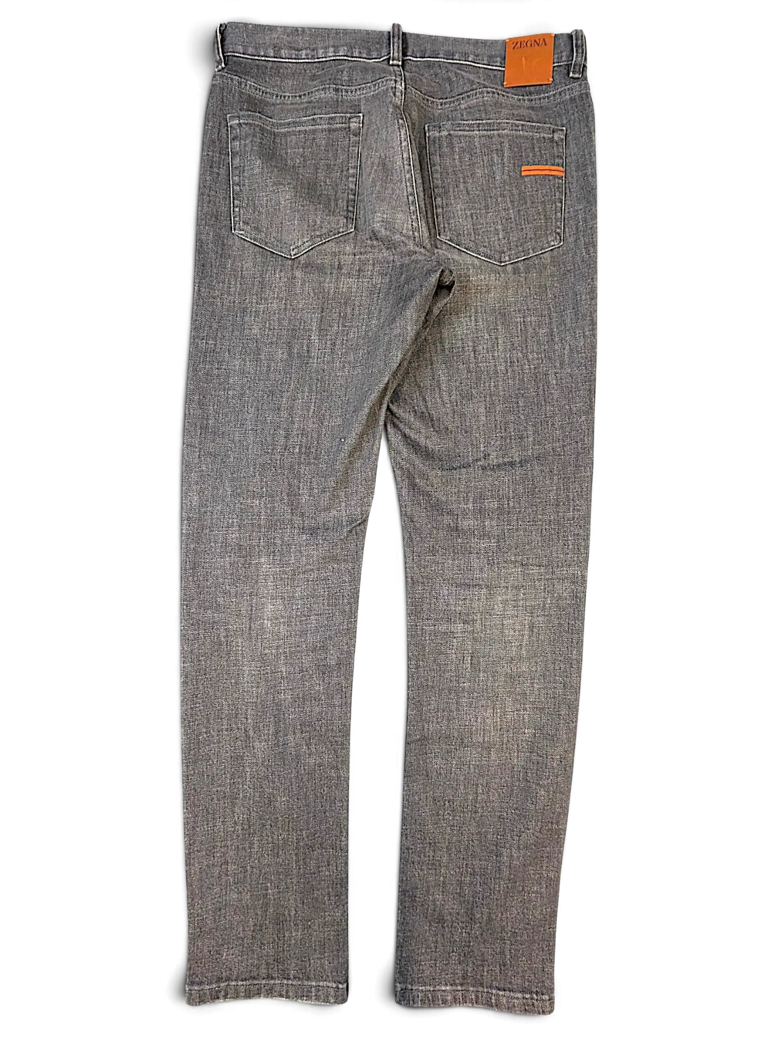 JAKE & IPI Zegna grey denim jeans featuring a leather back patch and orange accent stitching on the back pocket.